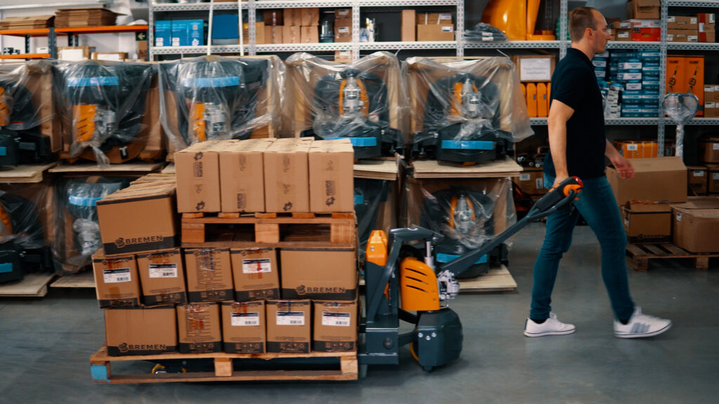 Homem usando uma paleteira para mostrar os benefícios do uso em um armazém de cargas